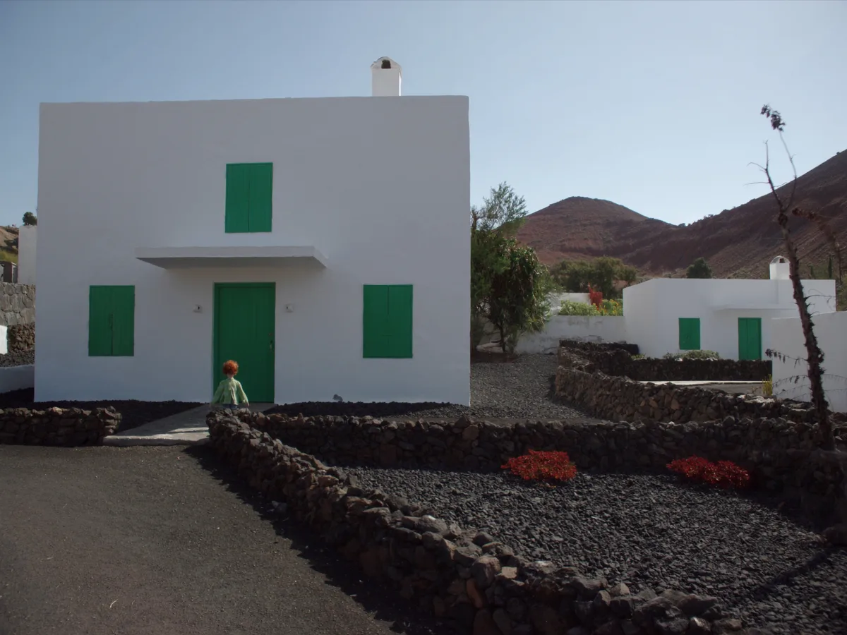 KI-generiertes Bild: weiße kubische Inselhäuser mit grünen Fensterläden zwischen schwarzem Vulkankies, typisch für Lanzarote